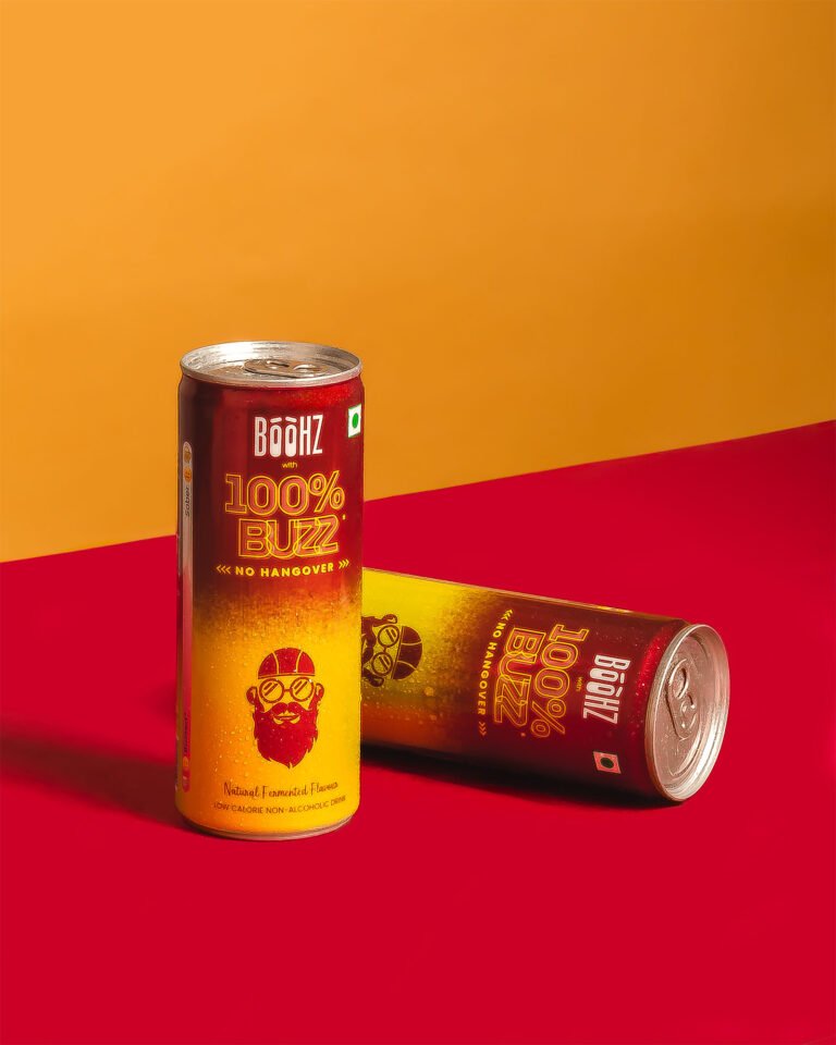 Commercial beverage product photography of BOOHZ energy drink cans on a vibrant yellow and red backdrop, shot by NiRam Creatives Bangalore.